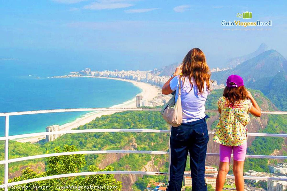 Imagem de duas turistas registrando em suas máquinas as belezas do Rio de Janeiro.