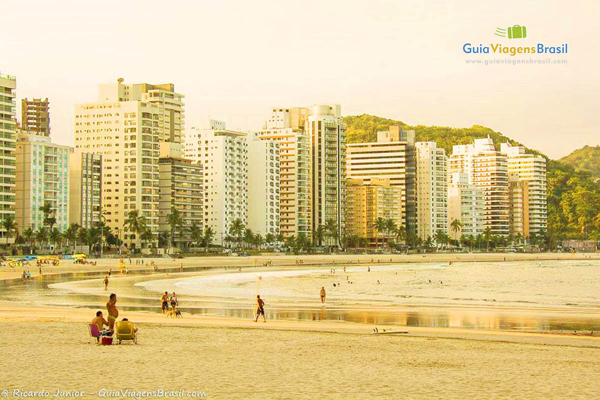 Imagem de turistas nas areias e no mar da Praia Astúrias.