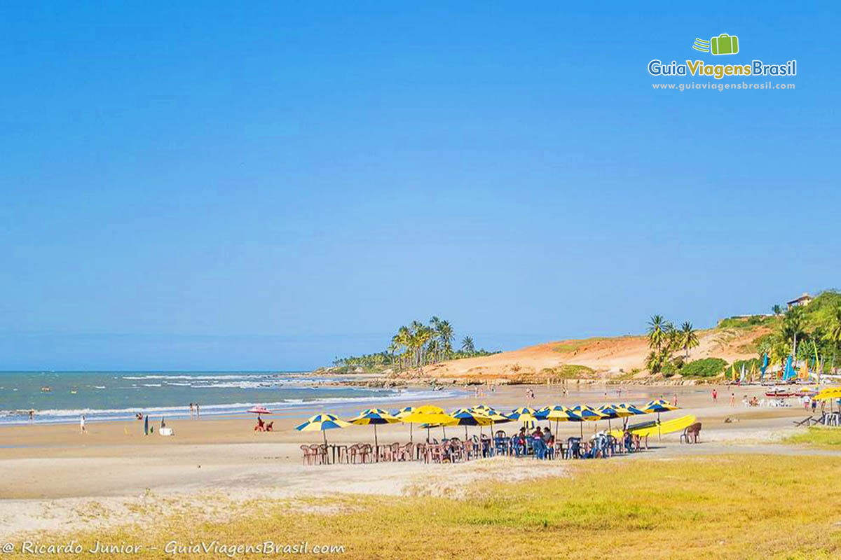 Imagem de vários guarda sol nas areias da praia.