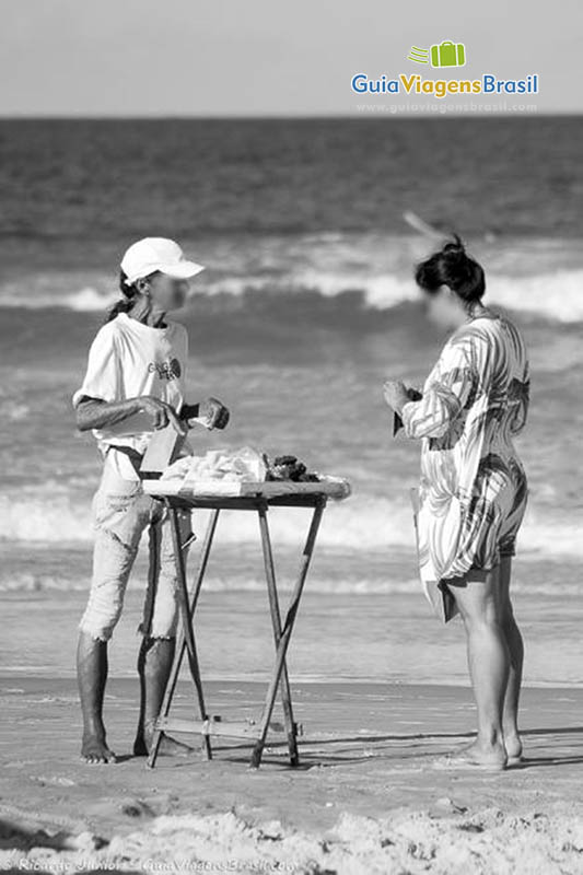 Imagem em preto e branco de vendedor de doces na bela praia.