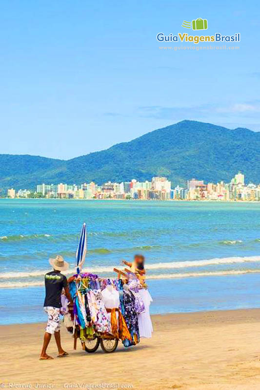 Imagem de vendedor ambulante andando pelas areias da Praia Itapema.