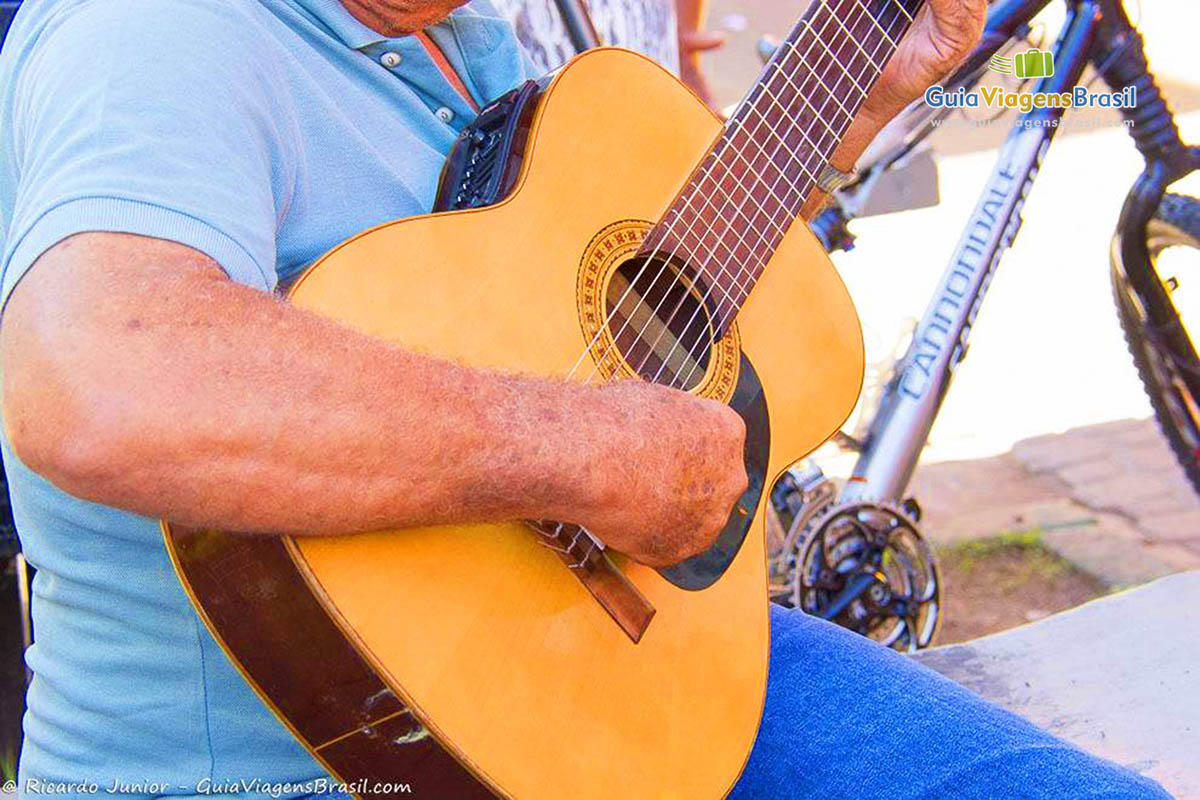 Imagem aproximada do músico tocando violão.