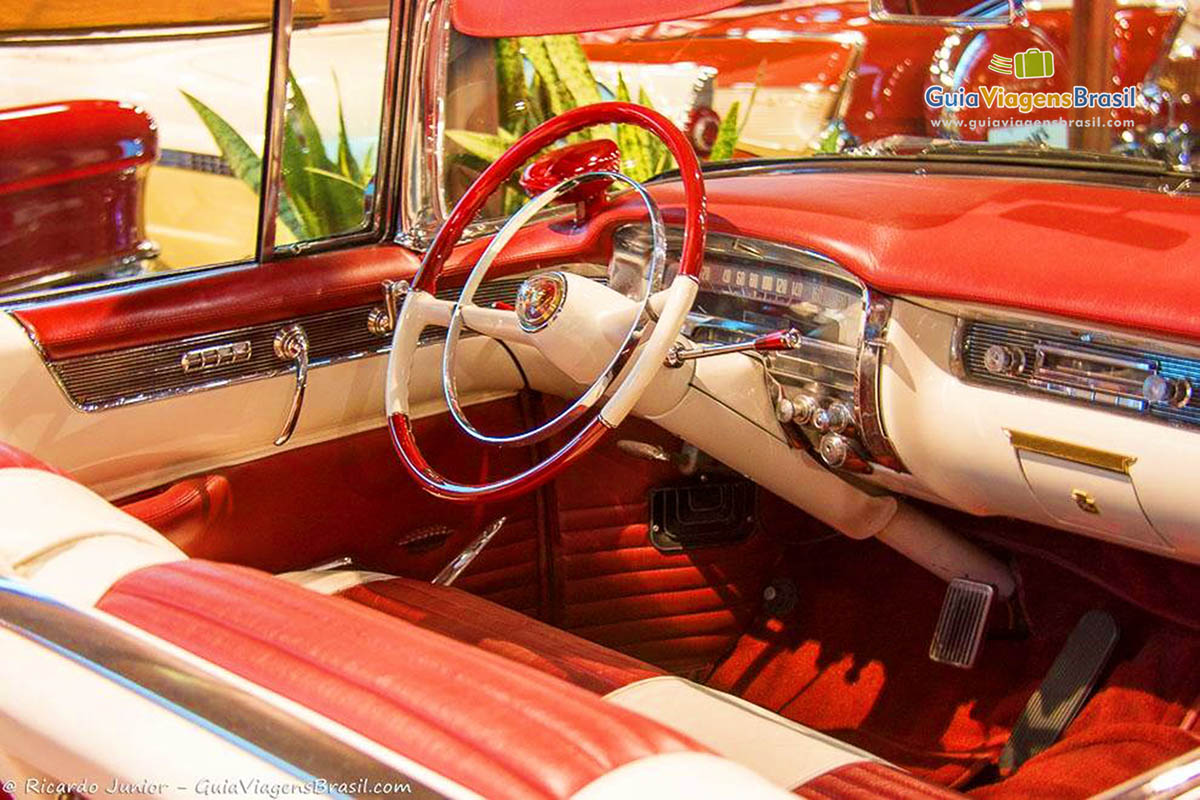 Imagem dos detalhes interno dos carros, painel, banco e acabamento interno em vermelho e branco. 