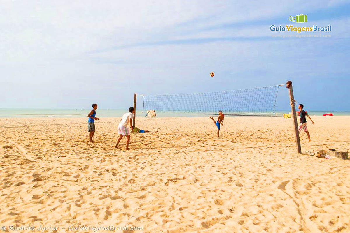 Imagem de pessoas jogando vôlei na praia.