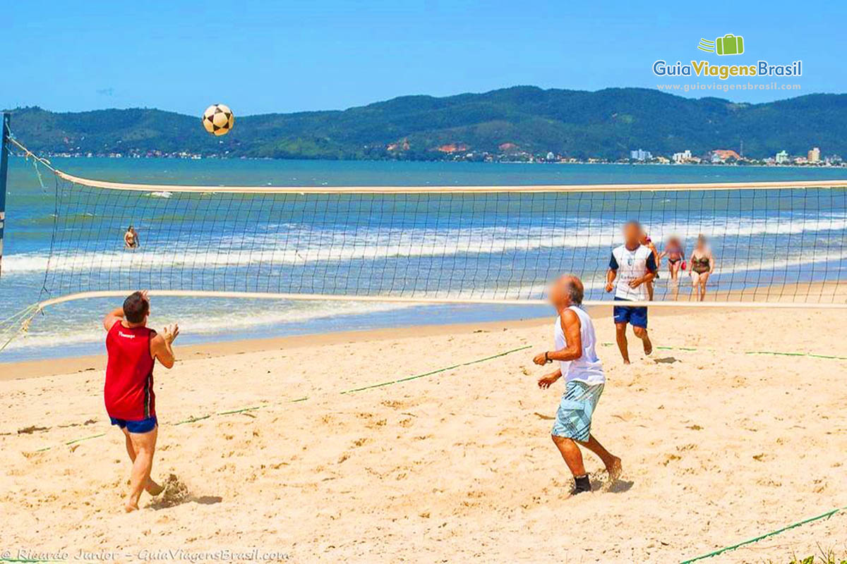 Imagem de pessoas jogando vôlei na praia.